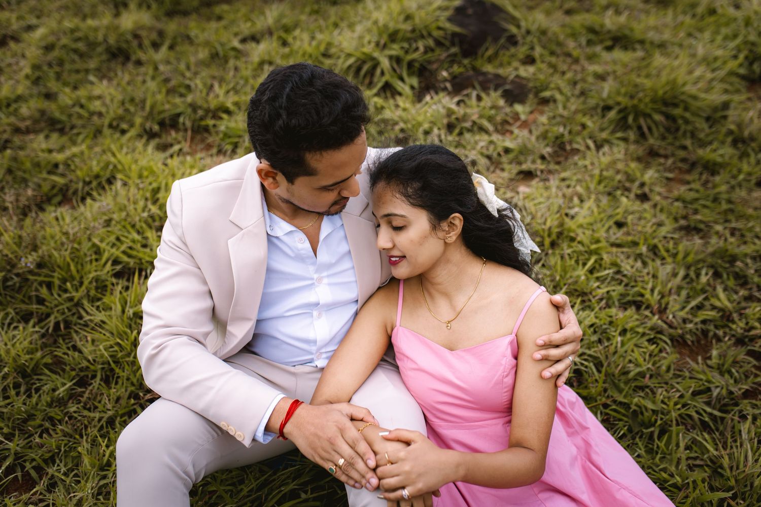 A couple sits together on grass during a romantic outdoor photo session.