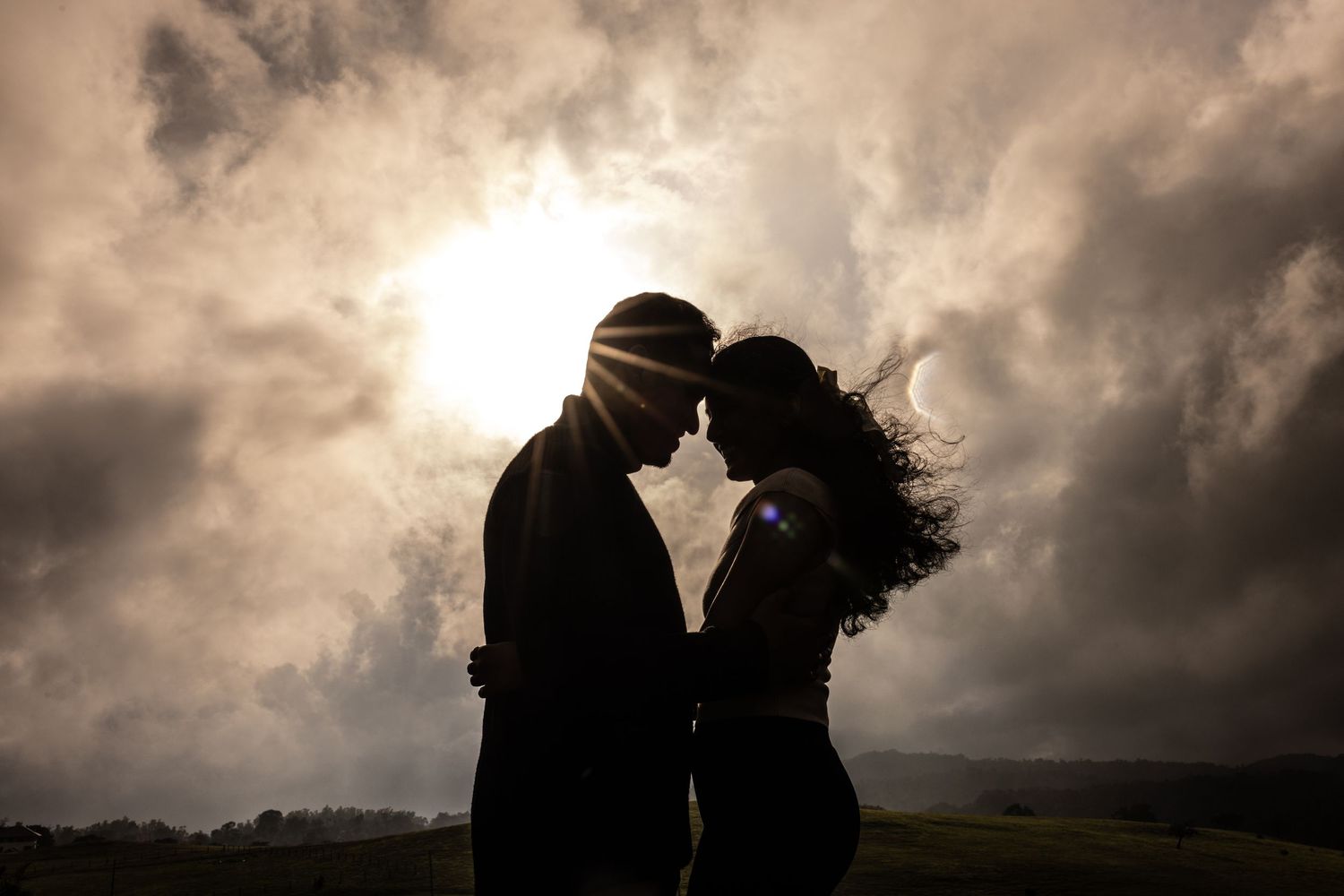 Dramatic silhouettes of a couple against stormy clouds during sunset.