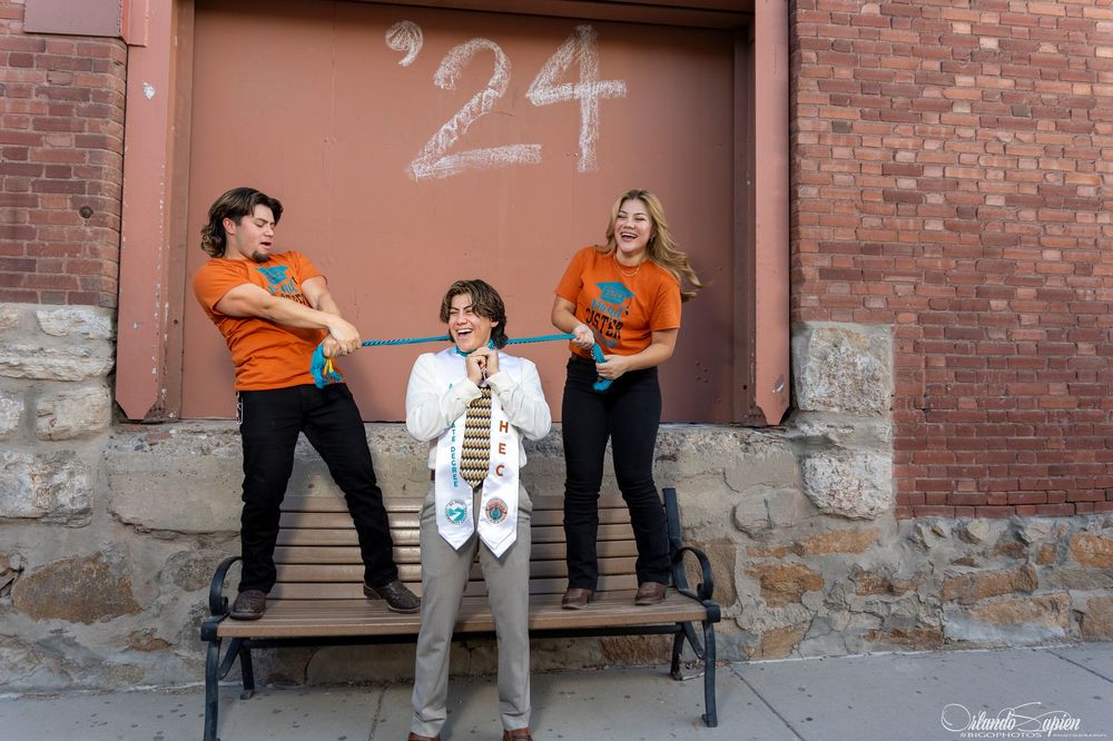 Graduation celebration photoshoot against brick wall with chalk numbers.