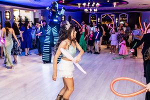 Guest dances at a quinceañera reception while a performer in an LED light-up costume and balloon twisters entertain the crowd.