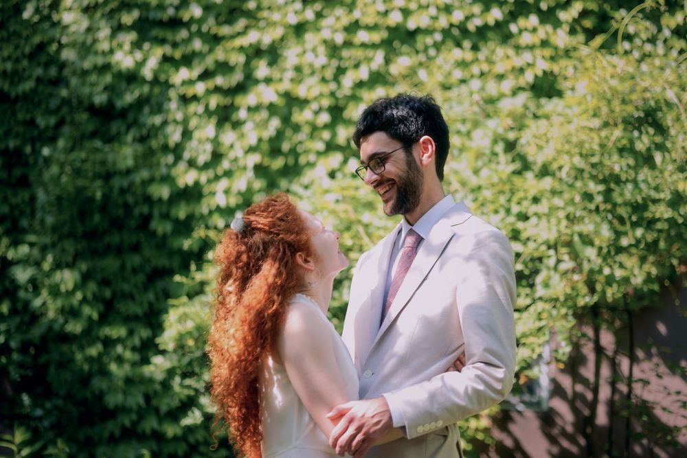 Romantic garden portrait of couple in formal attire against lush green foliage.