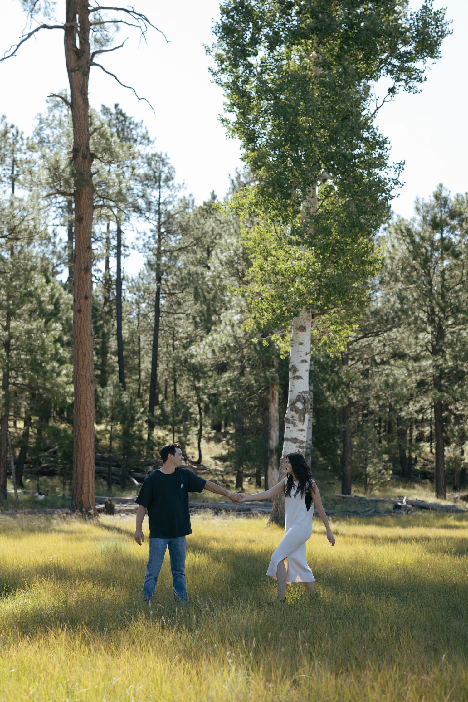 A couple stands together overlooking a scenic desert canyon with river below.