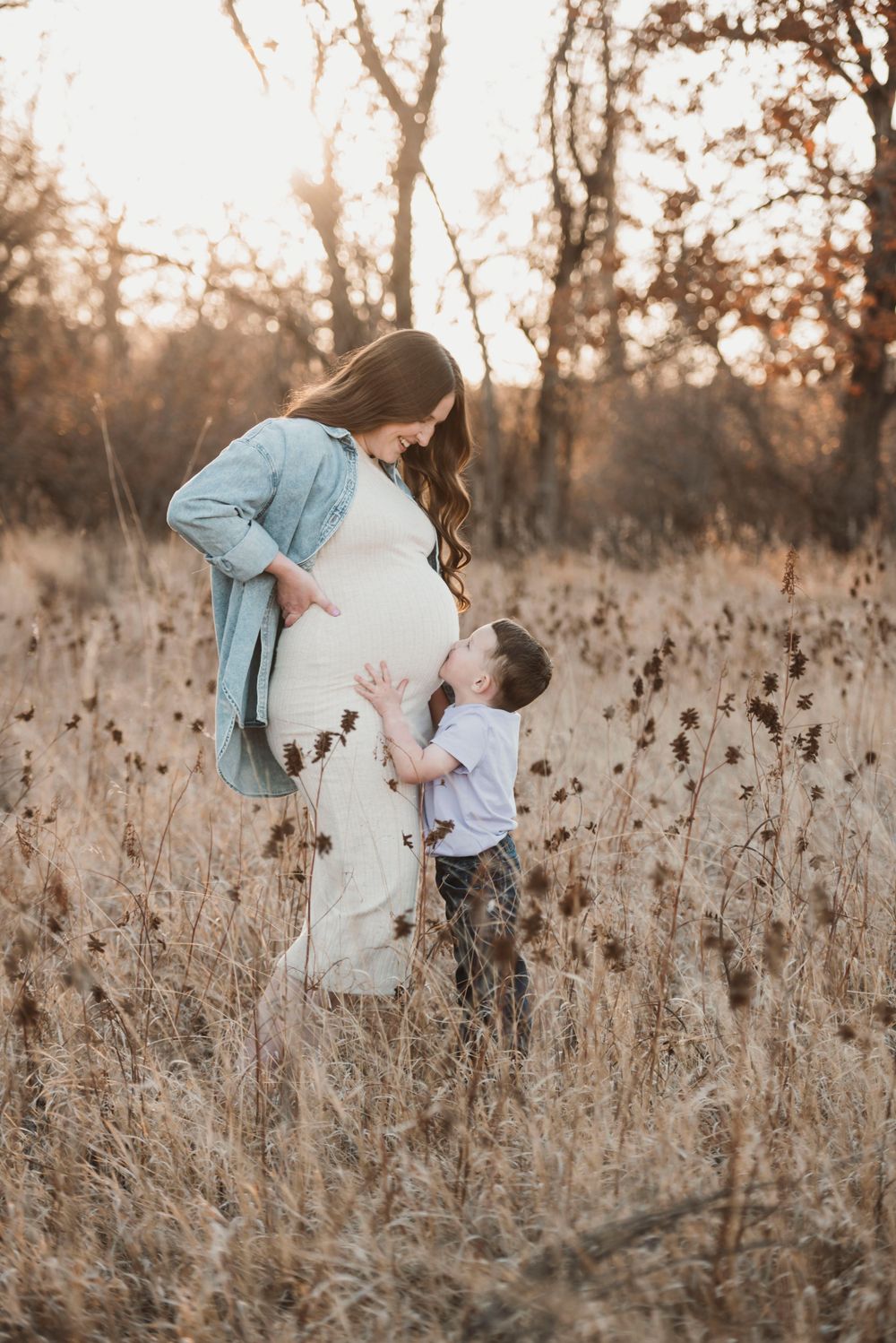 A tender moment between mother and child in a sunlit autumn field.
