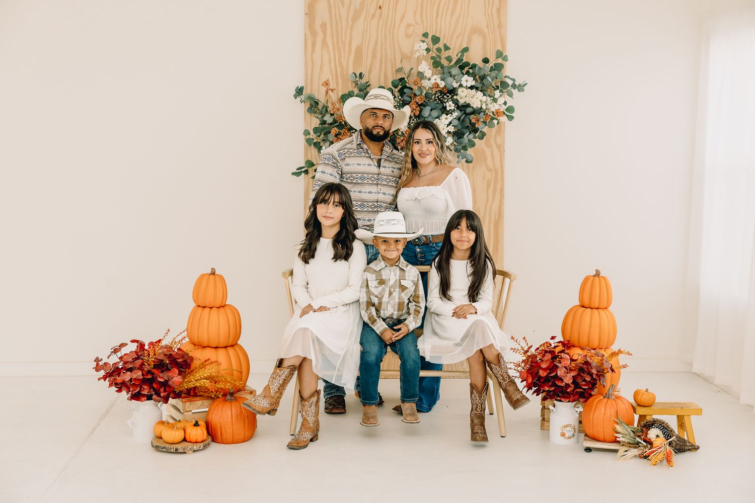 Indoor fall family photo of five in a Greeley, Colorado studio, with parents and three kids smiling together.