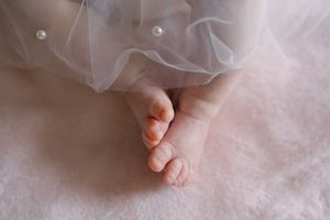 A series of close-up images showing tiny baby feet and toes against a soft pink blanket or fabric background.
