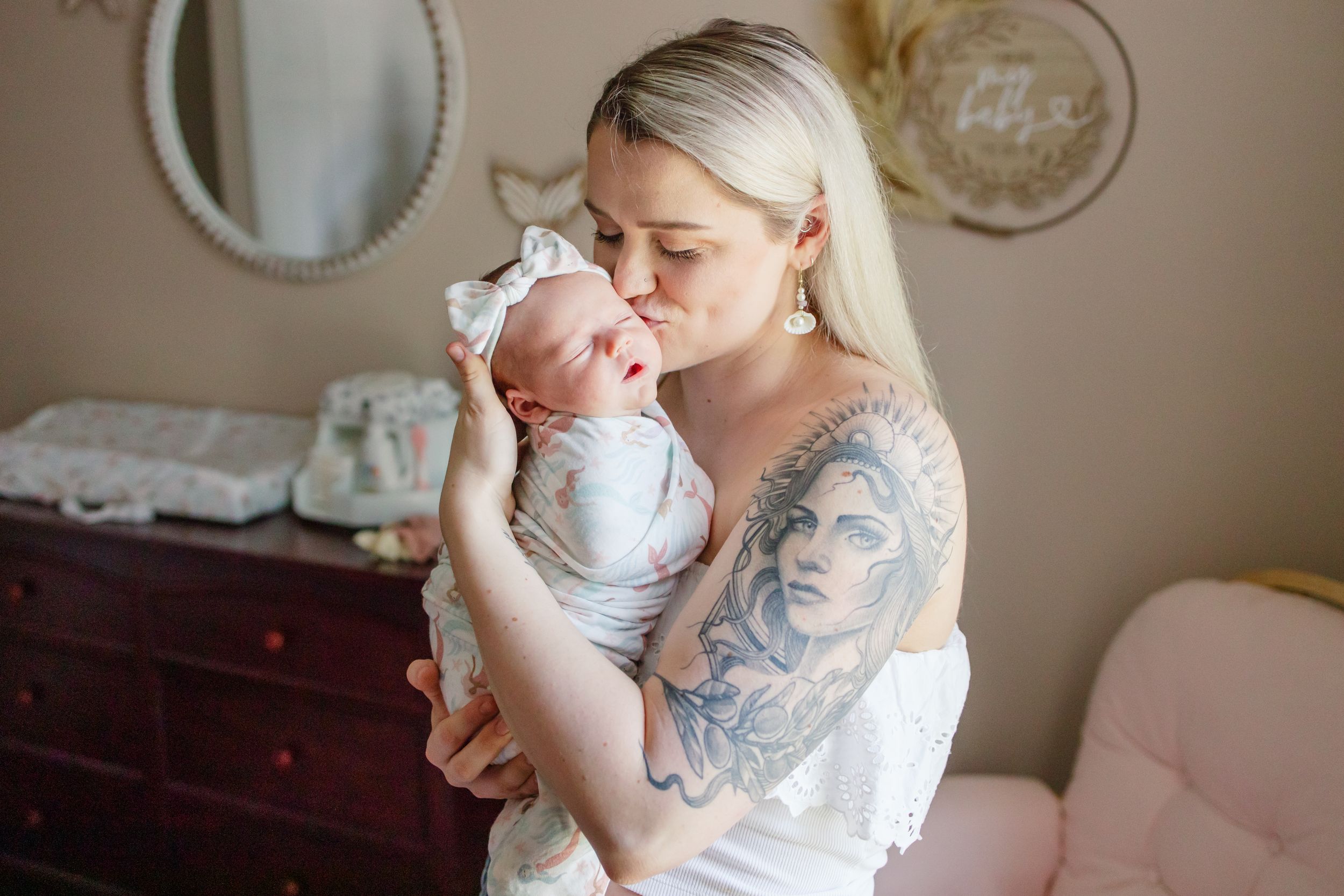 A tender moment between parent and infant in a softly lit nursery with vintage furniture and decor.