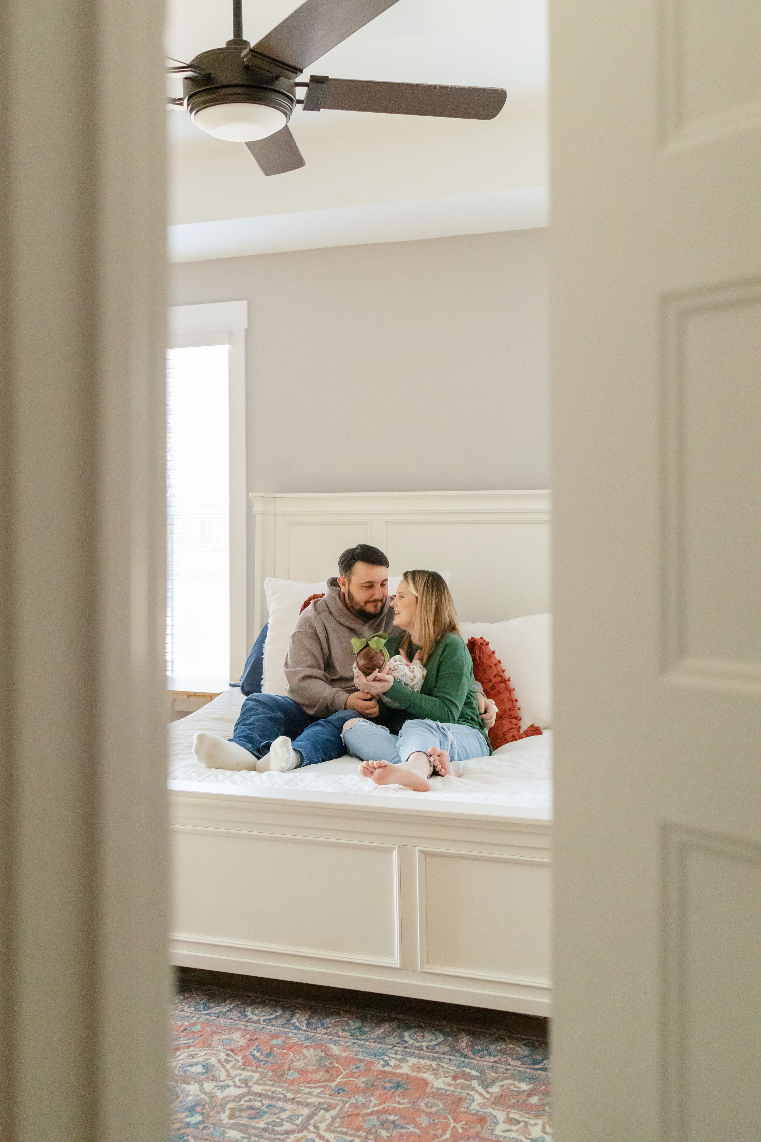 A couple sits together on a built-in window seat with natural light streaming in through white-framed windows.