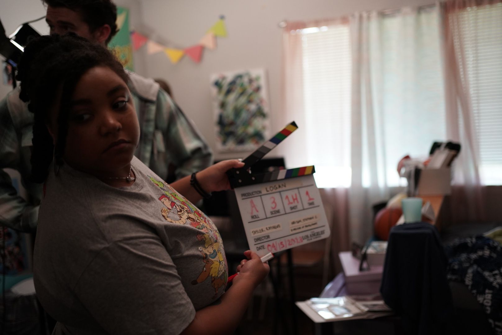Production crew member holding movie clapperboard during indoor film shoot.