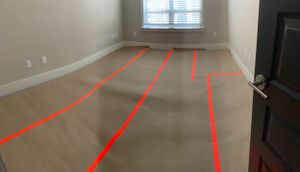 Empty film equipment storage room with red tape lines marked on hardwood floor.