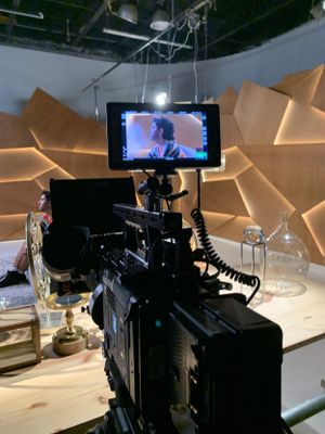 Professional video camera setup with monitor displaying footage on set with geometric backdrop.