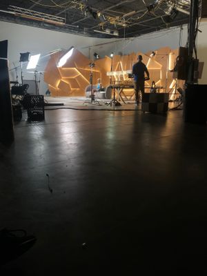 Dark studio space with geometric lighting patterns projected on the back wall.
