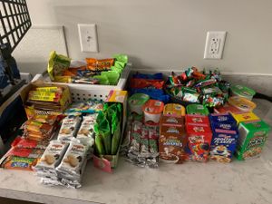 Collection of various snack packages and candy spread out on a counter surface.