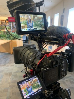 Professional camera setup with monitor displaying interview footage and microphone attachment.