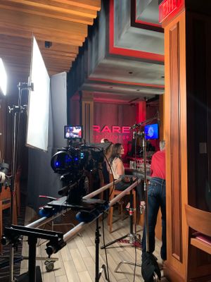 Professional film production setup with lighting and camera equipment in a dark room with red accents.