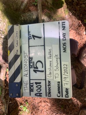 Film slate with production details lying on forest ground.
