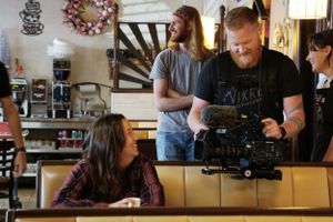 Film crew operating camera equipment in casual dining setting.