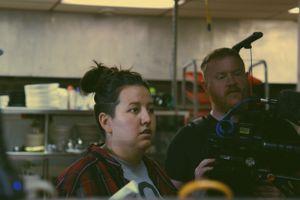 Film crew members working with professional camera equipment in indoor setting.