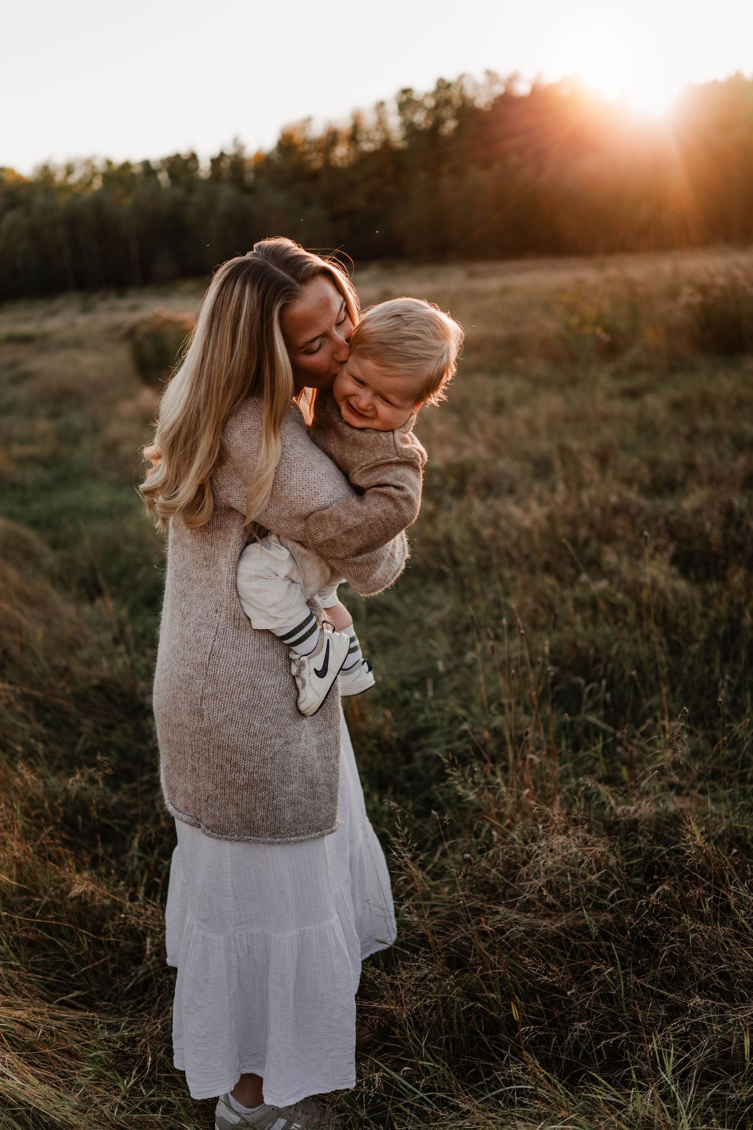 Mamma med sin son på en äng i solnedgången