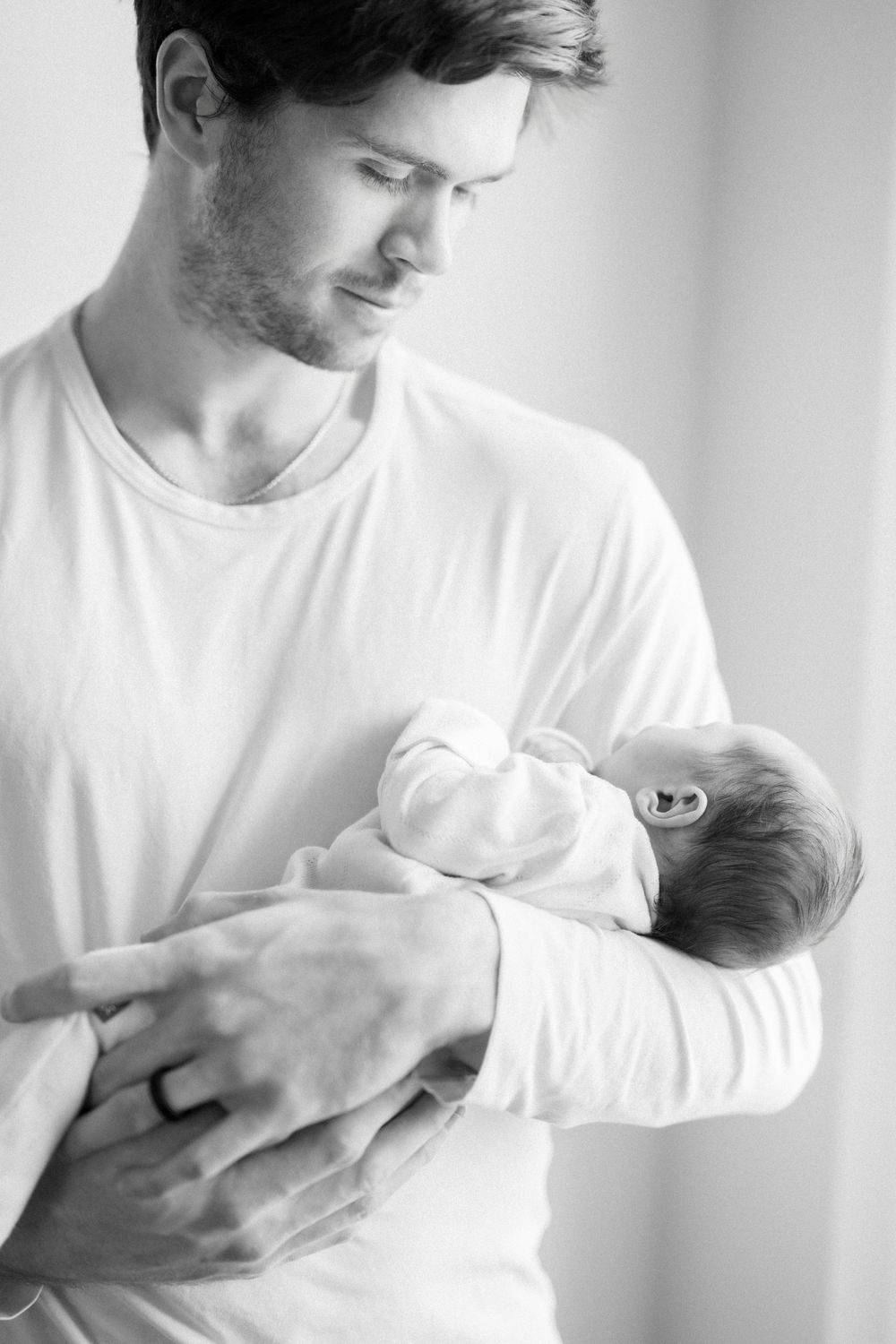 Father holding sleeping newborn during a lifestyle newborn session in Arlington Virginia