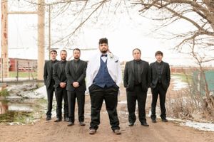 Groomsmen in formal attire pose outdoors during winter.