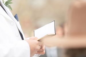 Close-up shot of someone holding white paper during wedding ceremony.