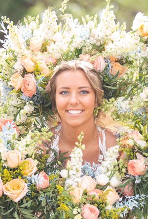 A stunning floral crown portrait featuring peach roses and delicate white blooms.