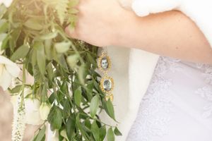 Close-up of bridal bouquet and peacock feather earrings.