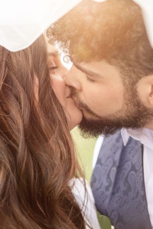 Romantic sunlit wedding kiss with soft golden lighting.