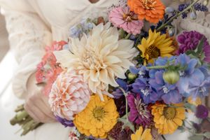 Vibrant wedding bouquet with dahlias, sunflowers, and purple blooms.