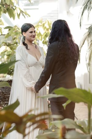 Wedding scene in greenhouse with greenery and natural lighting.
