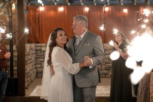 A couple shares a dance moment under twinkling lights at an indoor wedding venue.