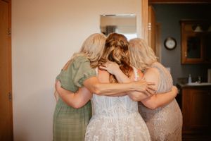 Bridesmaids in sage green dresses gather together during wedding preparations.