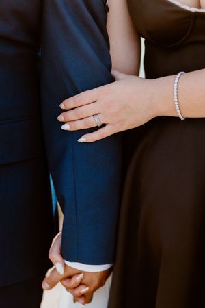 Close up of pearl bracelet and engagement ring with navy suit detail.