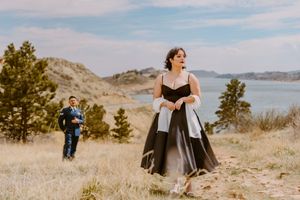 Dramatic dress contrast against mountain landscape during outdoor photoshoot.