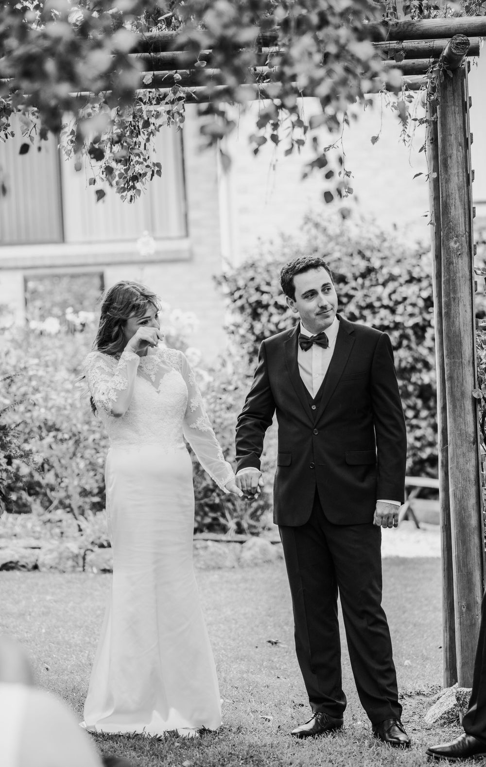 Black and white photo of couple sharing intimate moment during outdoor garden wedding ceremony.