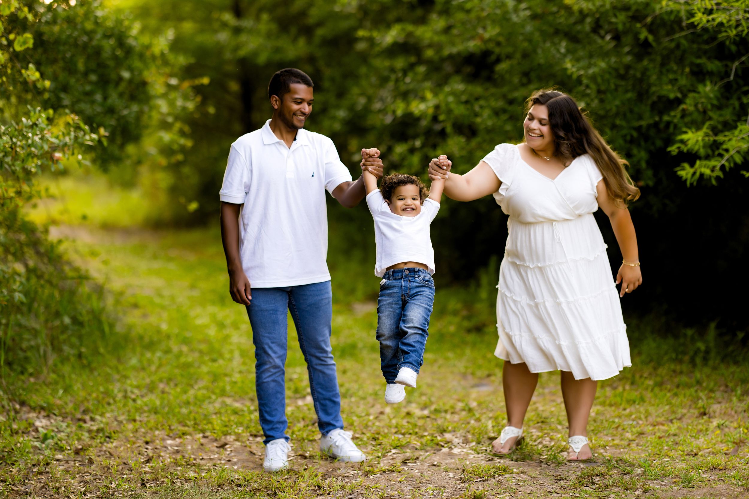 Family walking together on nature trail holding hands.