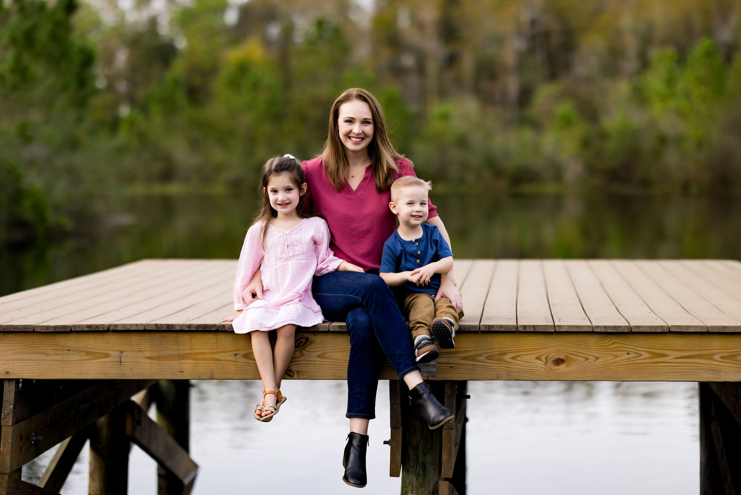 A family enjoys time together on a wooden bridge walkway during an outdoor photoshoot.