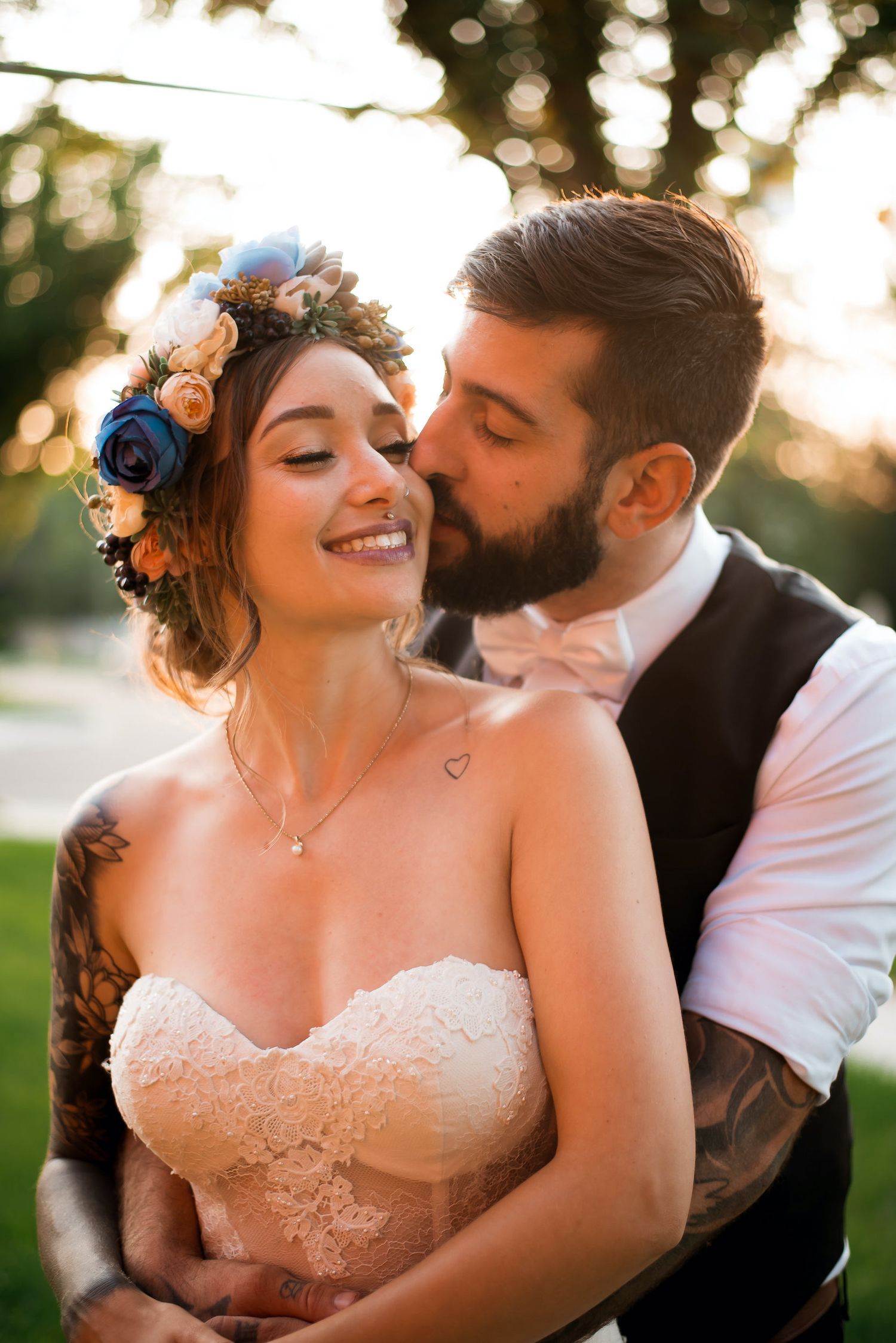 Romantic wedding photo of couple outdoors with bride wearing floral crown and lace dress.