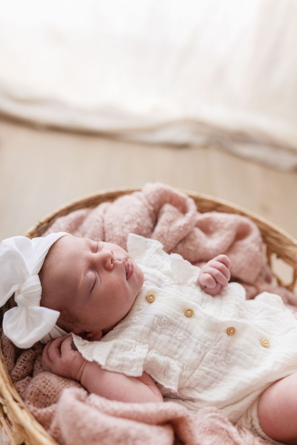 Nouveau-né fille dormant dans une panière en osier avec une tenue de créateur du studio, photographe bébé Niort.