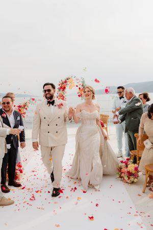 Wedding party celebrates on a rooftop terrace with pink flower petals being tossed in the air during a joyful ceremony.