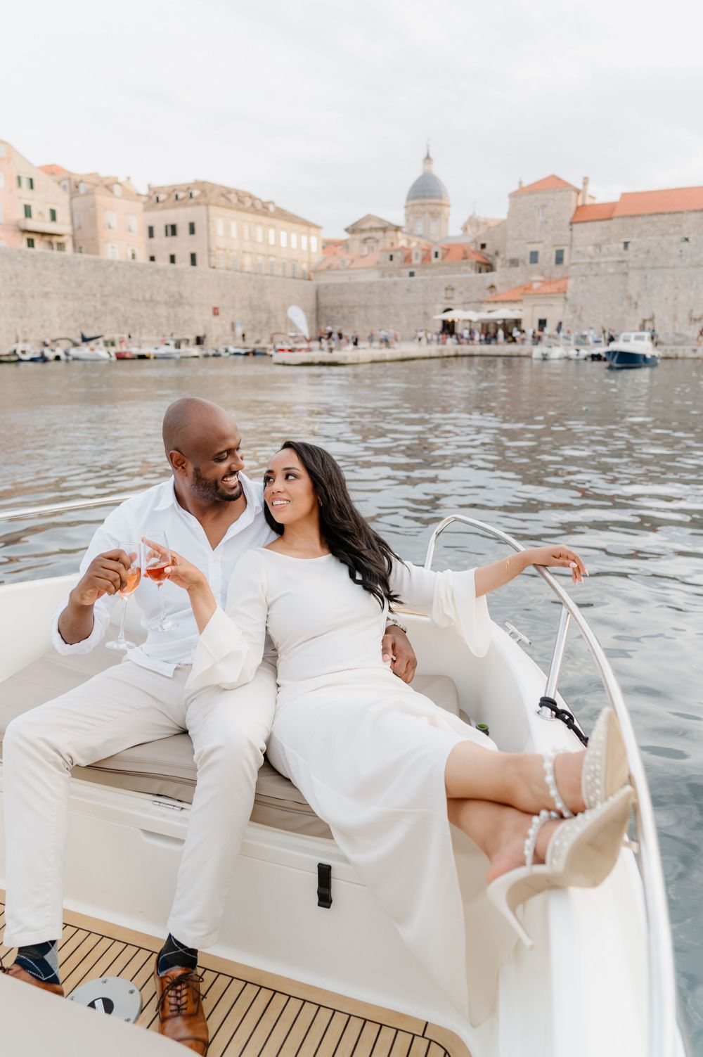 A romantic boat ride along the historic walls of Dubrovnik's harbor with couple dressed in white.