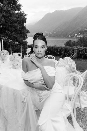A bride in a white wedding dress poses outdoors against a scenic mountain lake backdrop in a series of elegant photos.