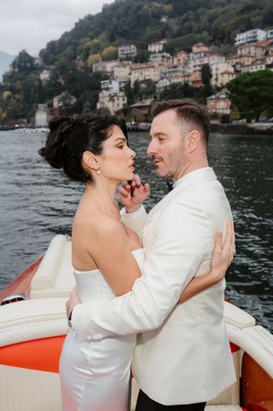 A romantic wedding couple shares intimate moments while sailing on a boat across Lake Como in Italy.