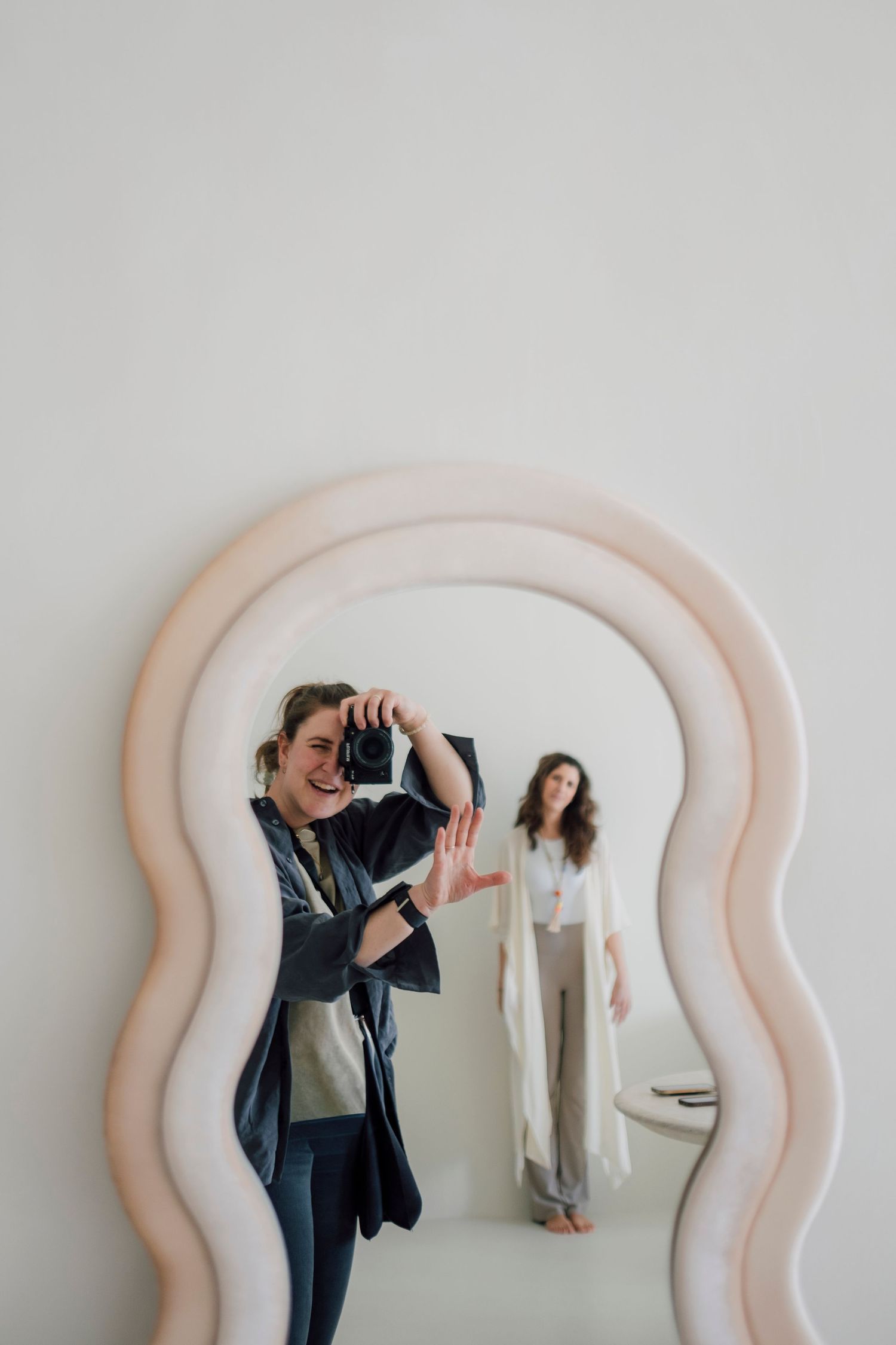 Four minimalist fashion photographs showing clothing displayed against curved pink wall panels in a retail setting.