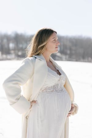 Pregnant mom in her backyard in the winter with the snow in the background | Connecticut Maternity Photographer.