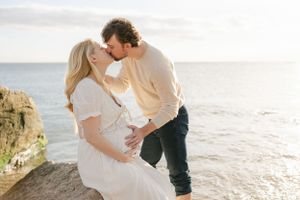 Couple kissing on the rocks at the beach | Connecticut Maternity Photographer.