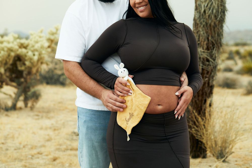 Close-up of couple holding yellow blanket during desert maternity photoshoot.