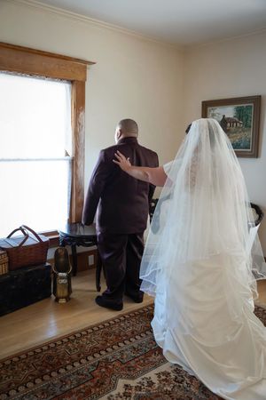 bride tapping groom on shoulder for first look
