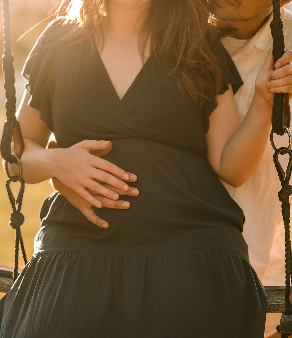 Silhouette of couple on swing set during golden hour sunset.