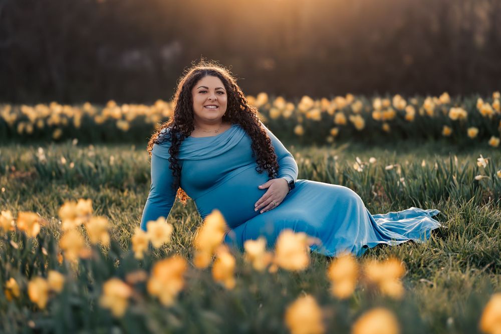 Person reclining among yellow daffodils in evening light.